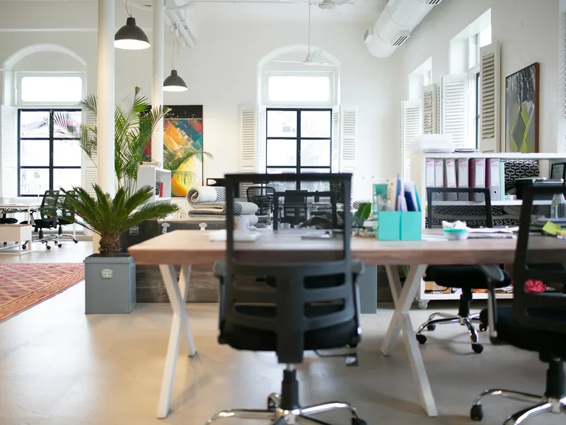 A bright, empty team office with shared desks and plants
